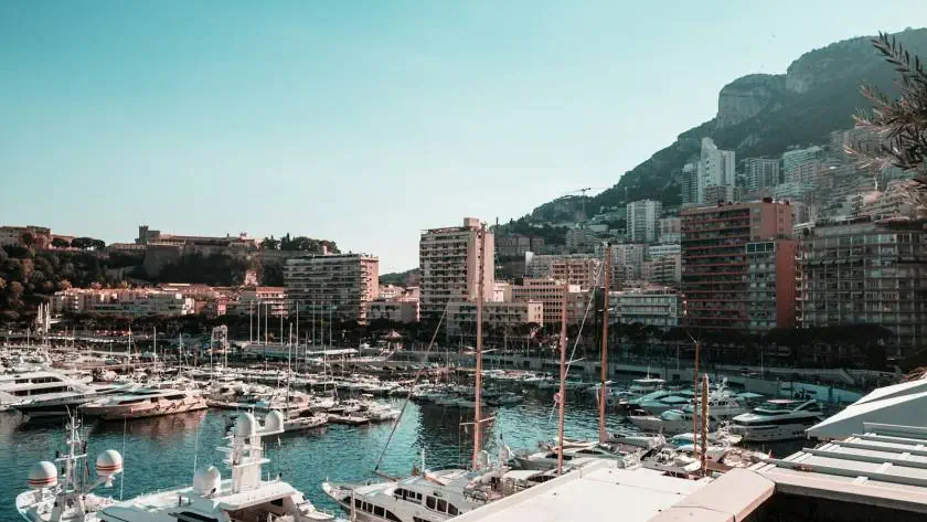 Vue du port de Monaco avec yachts et bâtiments modernes en arrière-plan.
