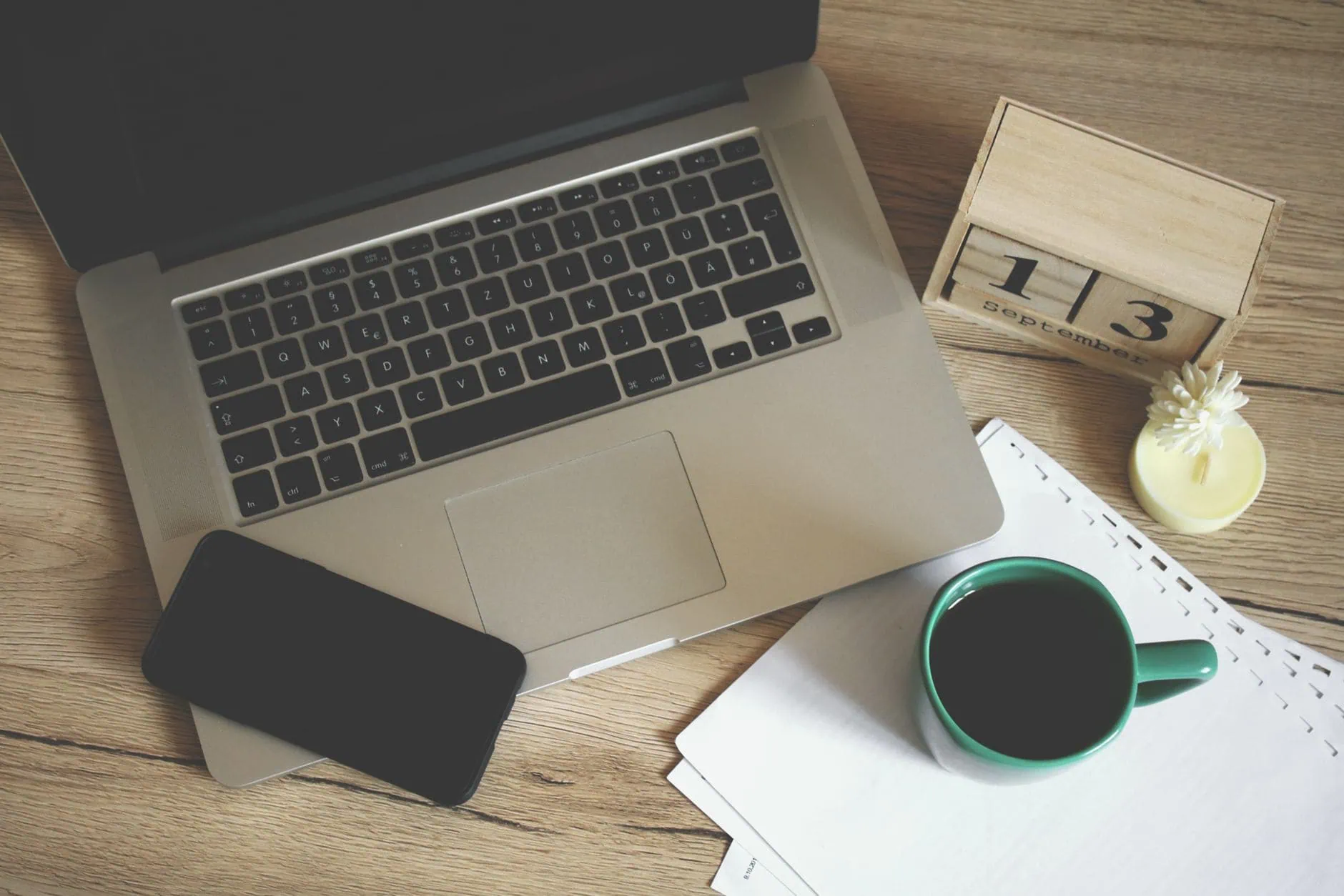 Les 10 choses à ne jamais faire avec votre Mac (Guide 2026) 1 Tasse de café posée juste à côté d'un MacBook fermé sur un bureau, risque de dégât liquide
