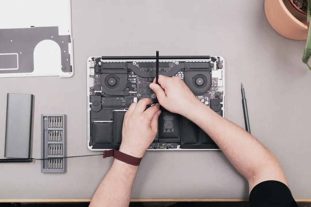 Pourquoi faire les mises à jour macOS (et ce qui arrive si vous ne les faites pas) — Guide 2026 1 Technicien intervenant avec un tournevis sur un MacBook après une mise à jour macOS qui a échoué